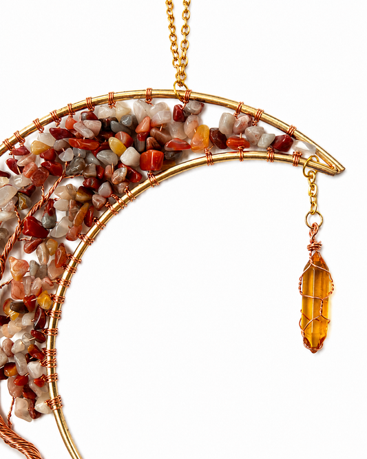 A crystal dream catcher hanging decoration filled with small polished natural stones in red, orange, white, and brown, with a dangling amber crystal charm, shown on a white background.