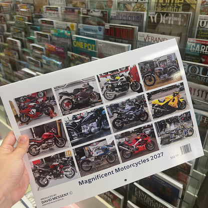 A hand holds a printed calendar or booklet titled "Magnificent Motorcycles 2027" in front of a store shelf filled with magazines. The printed sheet shows a grid of motorcycle photos and the name David Messent at the bottom.