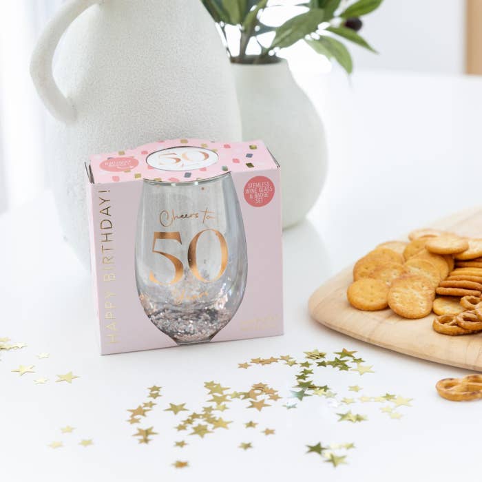 Celebration 50th Glitter Stemless Glass & Badge Set by Splosh in a styled birthday setting