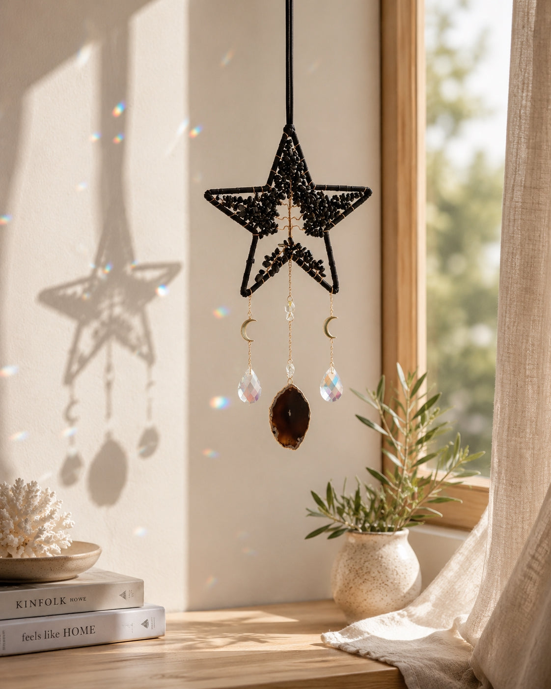 Black star-shaped natural crystal dream catcher hanging beside a sunlit window as bold celestial-inspired boho home decor.