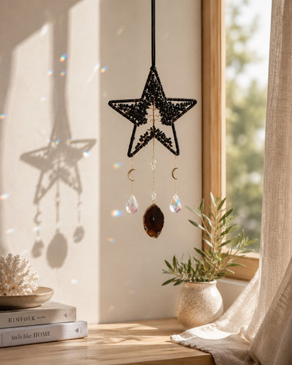 Black star-shaped natural crystal dream catcher hanging beside a sunlit window as bold celestial-inspired boho home decor.