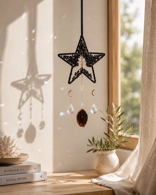 Black star-shaped natural crystal dream catcher hanging beside a sunlit window as bold celestial-inspired boho home decor.