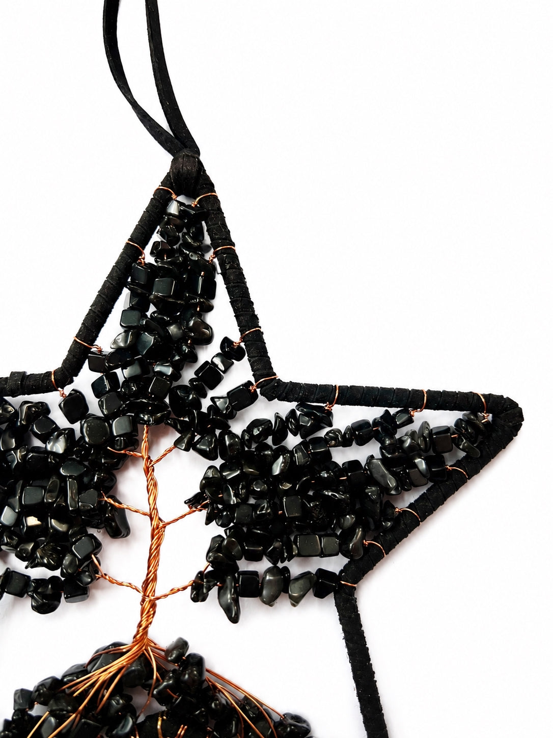 Close-up of a black star-shaped dream catcher handcrafted with dark natural crystal chips, copper wire and tree of life details.