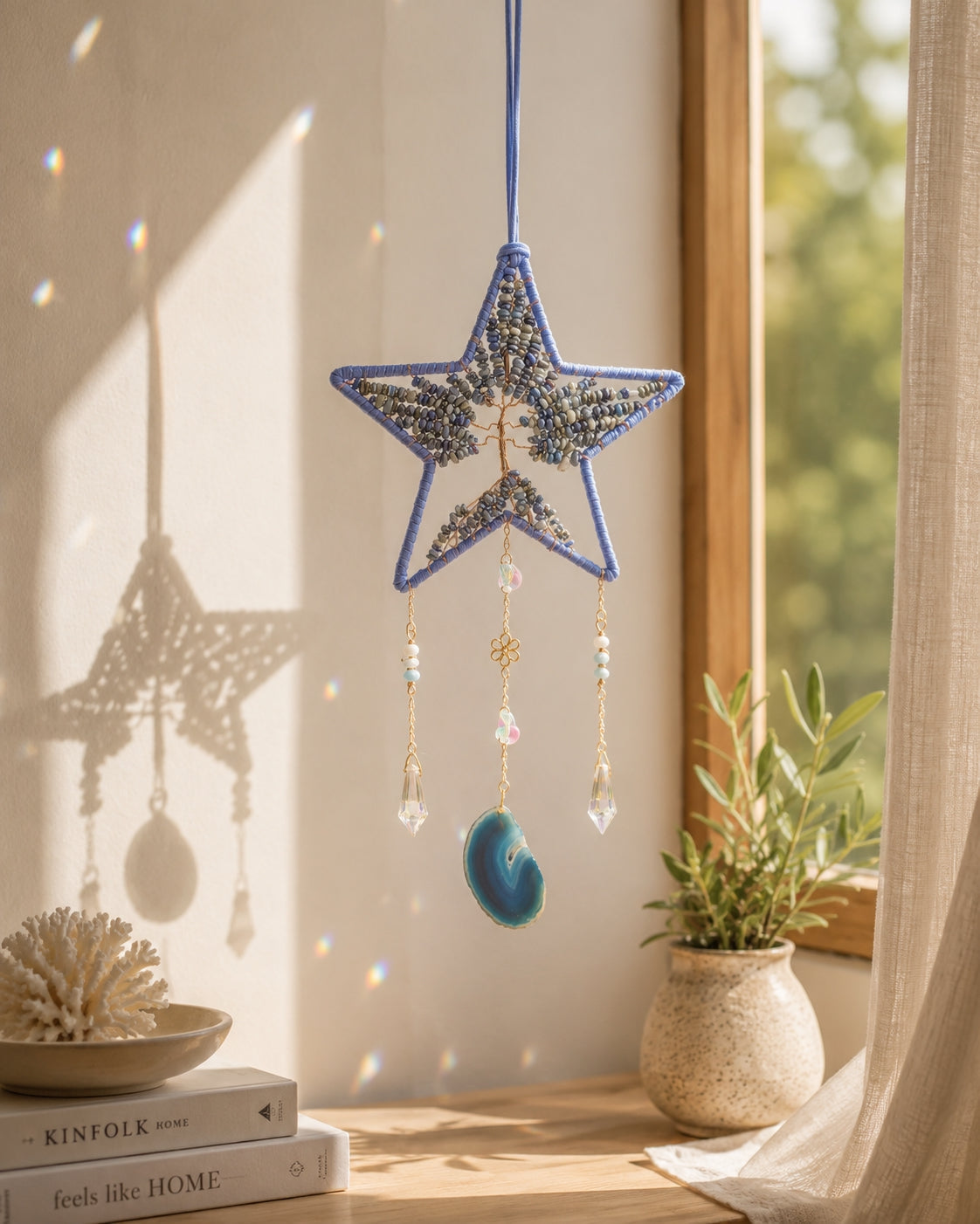 Blue star-shaped natural crystal dream catcher hanging beside a sunlit window as whimsical celestial-inspired boho home decor.