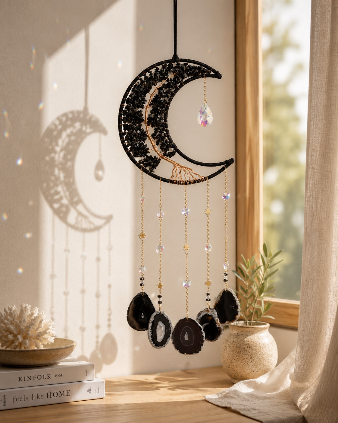 Black crescent moon crystal dream catcher hanging in a warm sunlit room as bold and elegant boho home decor.