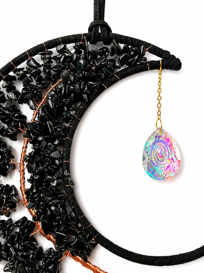 Close-up of a black crescent moon dream catcher handcrafted with dark natural crystal chips and a faceted rainbow crystal ball.