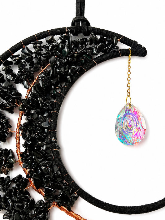 Close-up of a black crescent moon dream catcher handcrafted with dark natural crystal chips and a faceted rainbow crystal ball.