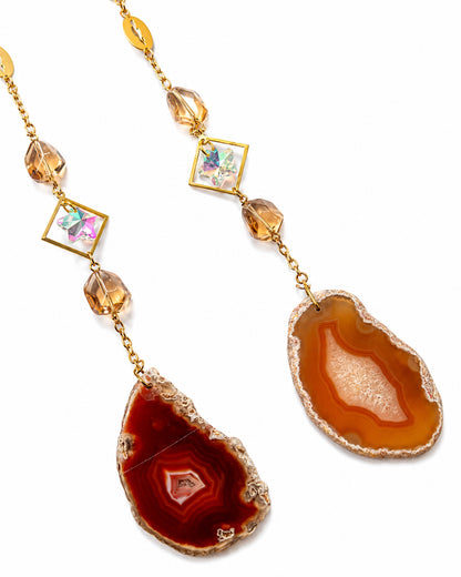 Close-up of warm orange and red natural agate slice pendants with gemstone beads from a crescent moon crystal dream catcher.