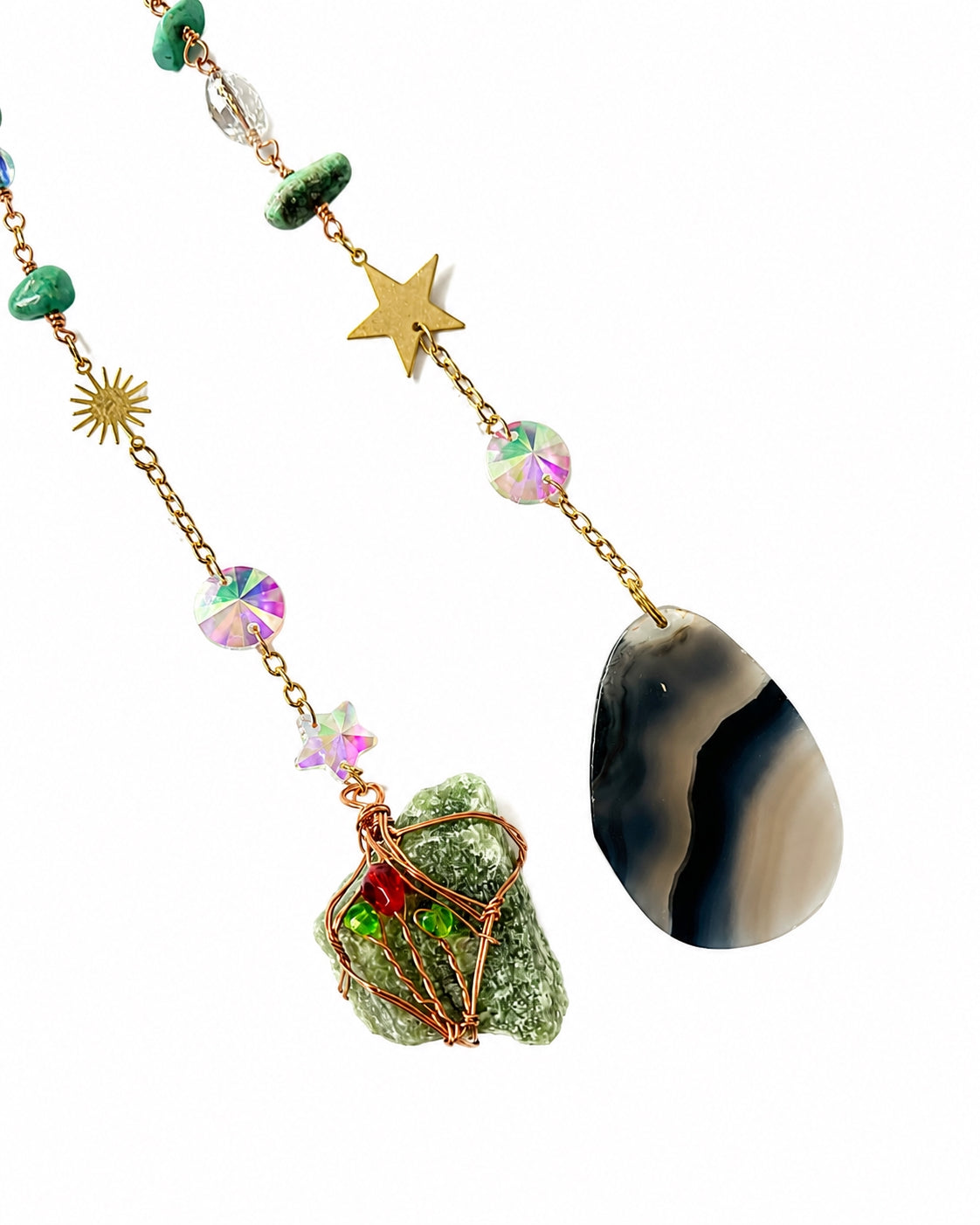 Close-up of colourful gemstone bead strands and dark natural stone pendants hanging from a turquoise crescent moon crystal dream catcher.