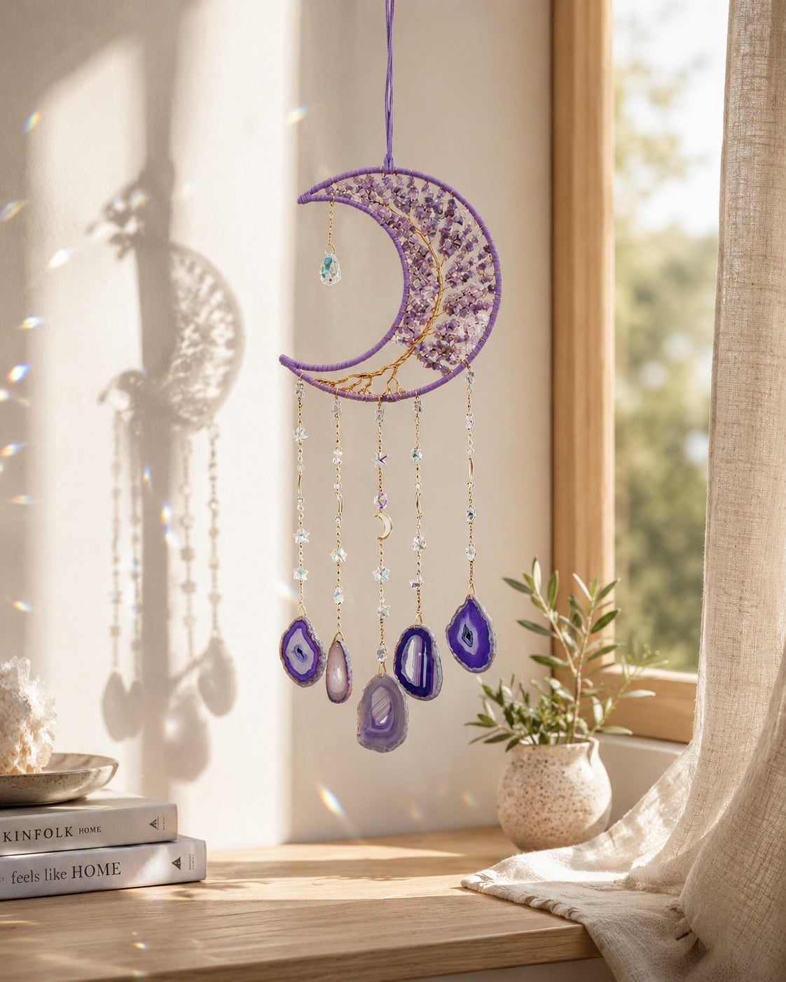 Purple crescent moon natural crystal suncatcher hanging beside a bright window and adding colourful detail to a peaceful room.