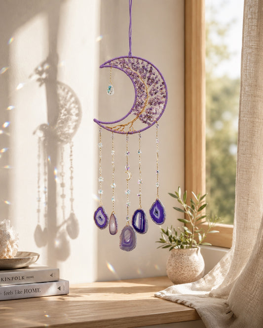 Purple crescent moon natural crystal suncatcher hanging beside a bright window and adding colourful detail to a peaceful room.