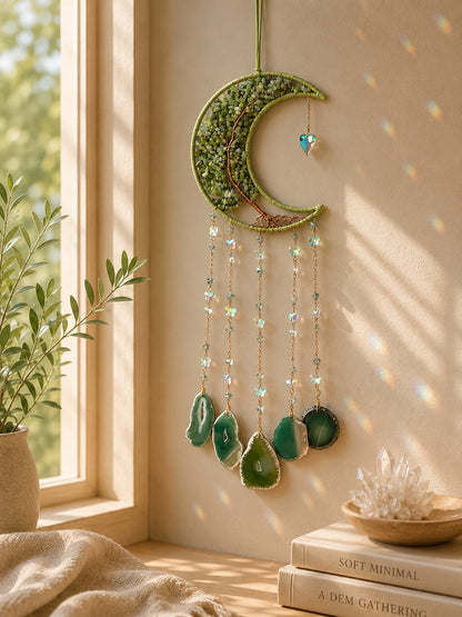Green crescent moon crystal dream catcher hanging beside a sunlit window as vibrant botanical-inspired boho home decor.