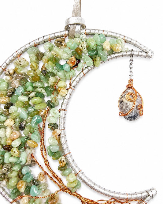 Close-up of a green and earthy crescent moon dream catcher handcrafted with colourful natural crystal chips and gold-toned wire.