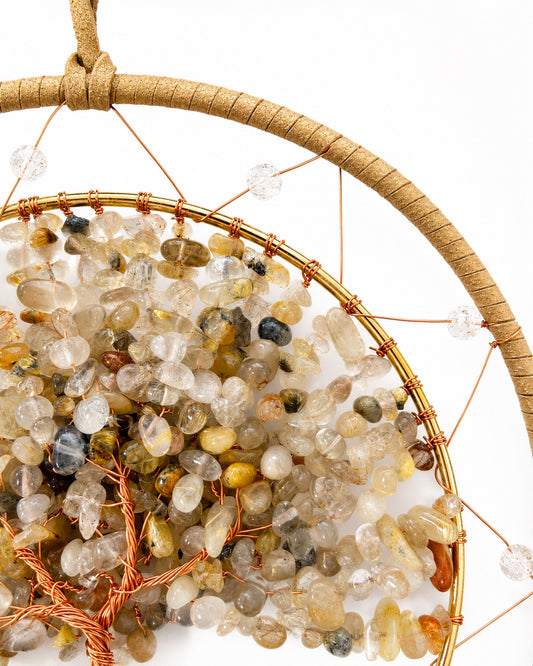 Close-up of a round crystal dream catcher handcrafted with neutral natural gemstone chips, gold-toned wire and layered circular frames.