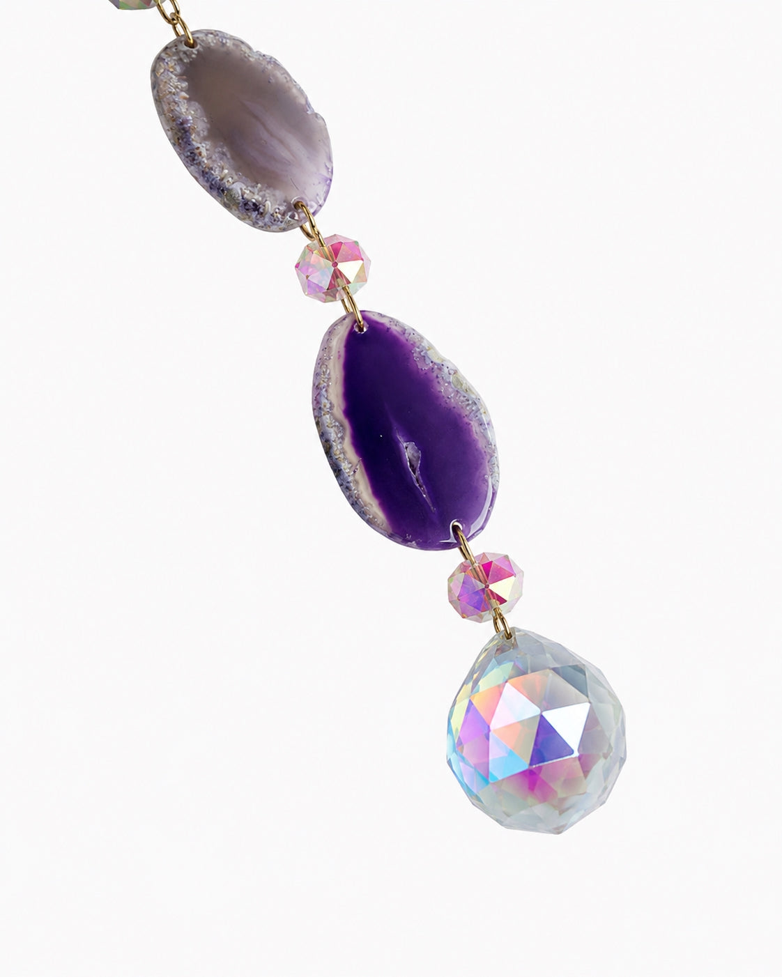 Close-up of purple natural gemstone beads and a faceted rainbow crystal prism hanging from a crescent moon crystal dream catcher.