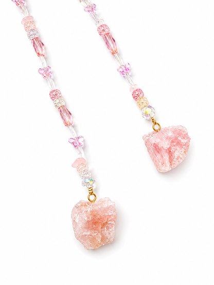 A beaded hanging pendant featuring light pink raw crystal pendants and small butterfly charms, strung with clear beads and iridescent accents on a white background.