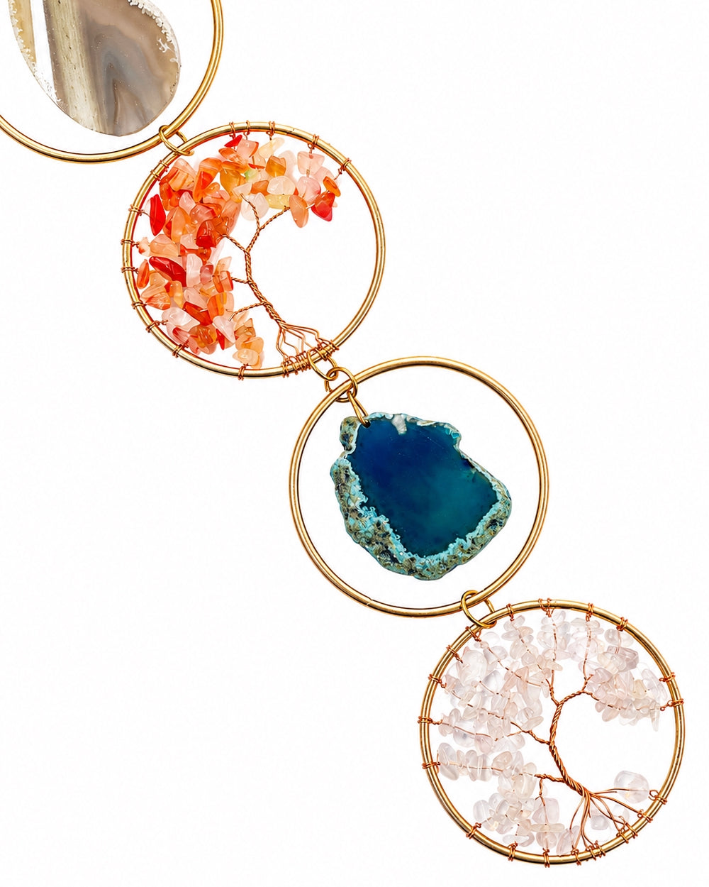 Close-up of a colourful natural crystal suncatcher featuring a red tree of life, blue agate slice and gold-toned circular frames.