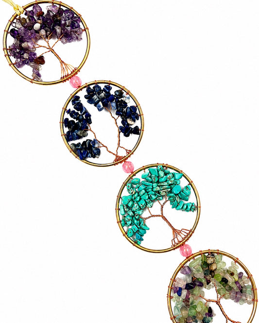 Close-up of colourful natural crystal chip trees set in gold-toned circular frames.