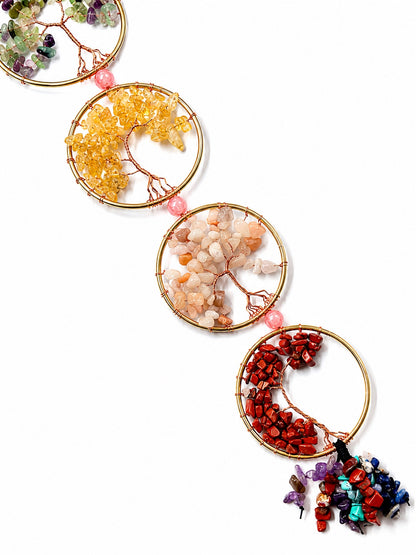 Close-up of colourful natural crystal chip trees set in gold-toned circular frames on a white background.
