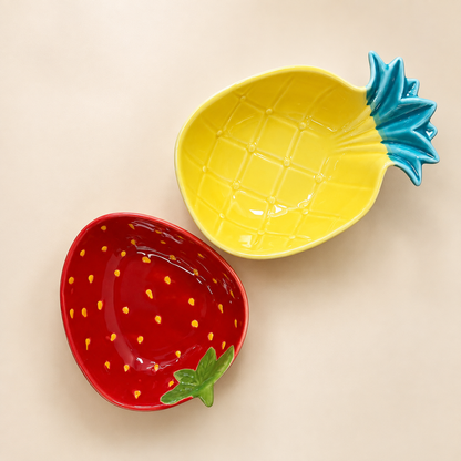 Two ceramic bowls shaped like a pineapple and a strawberry, displayed on a light beige background.