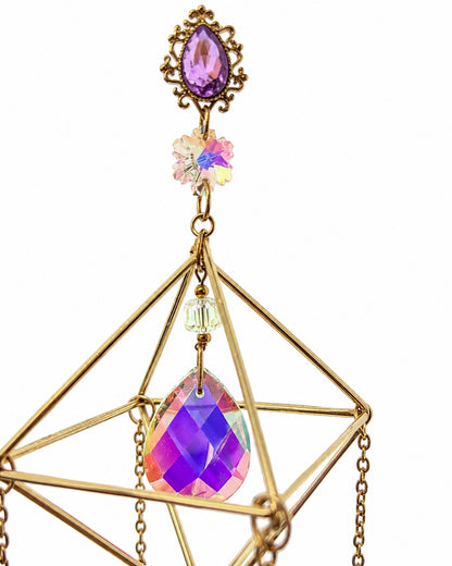 Close-up of a colourful faceted crystal suspended inside the handcrafted gold-toned geometric frame of a decorative suncatcher.