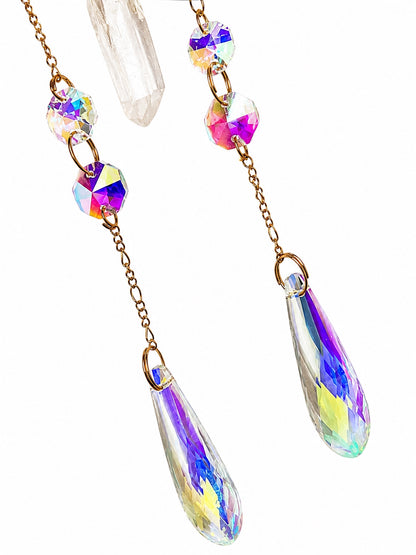 Close-up of colourful gemstone beads and iridescent teardrop crystal prisms hanging from a handcrafted natural crystal suncatcher.