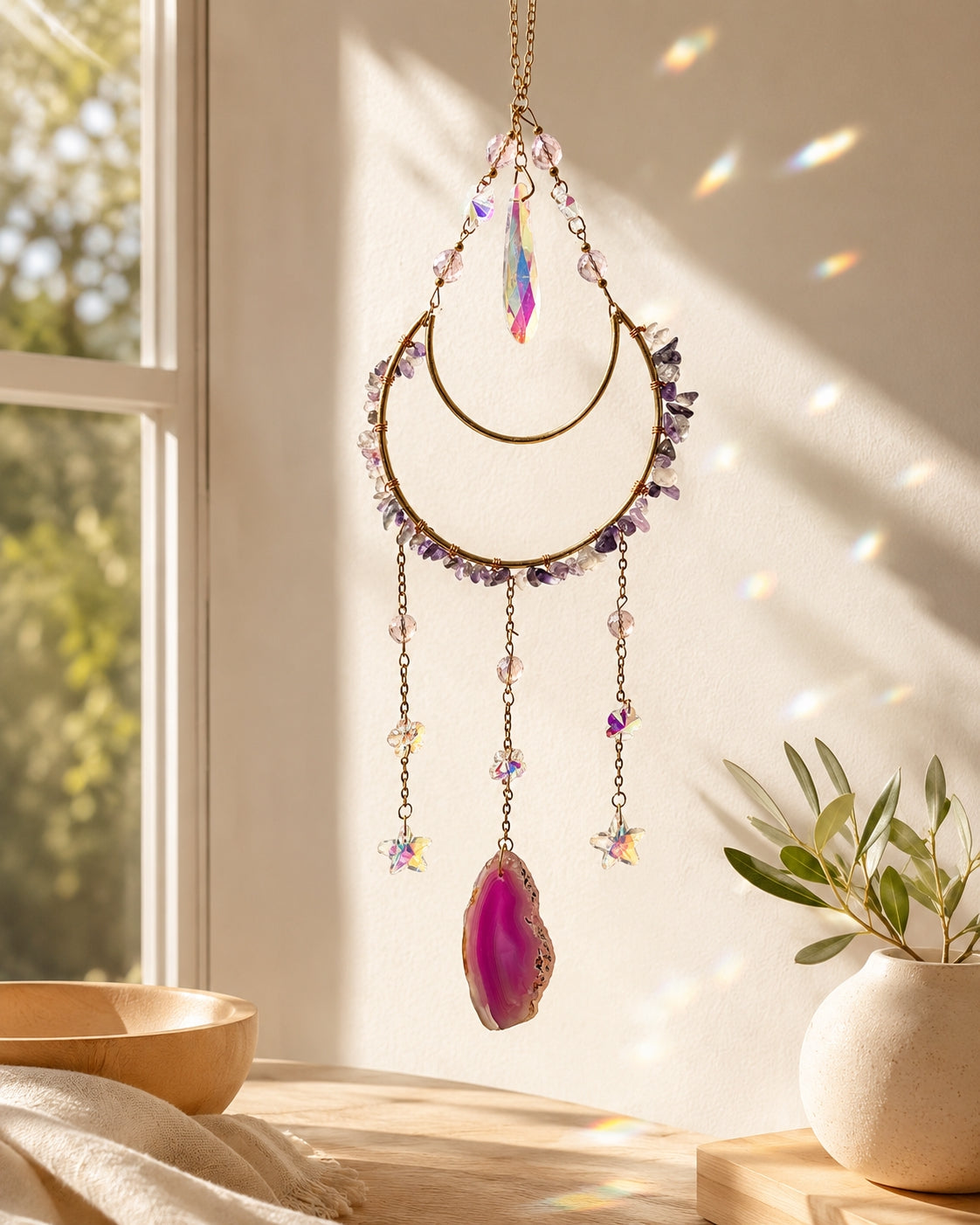 Colourful crystal suncatcher with a pink agate pendant hanging by a sunlit window as elegant boho home decor.